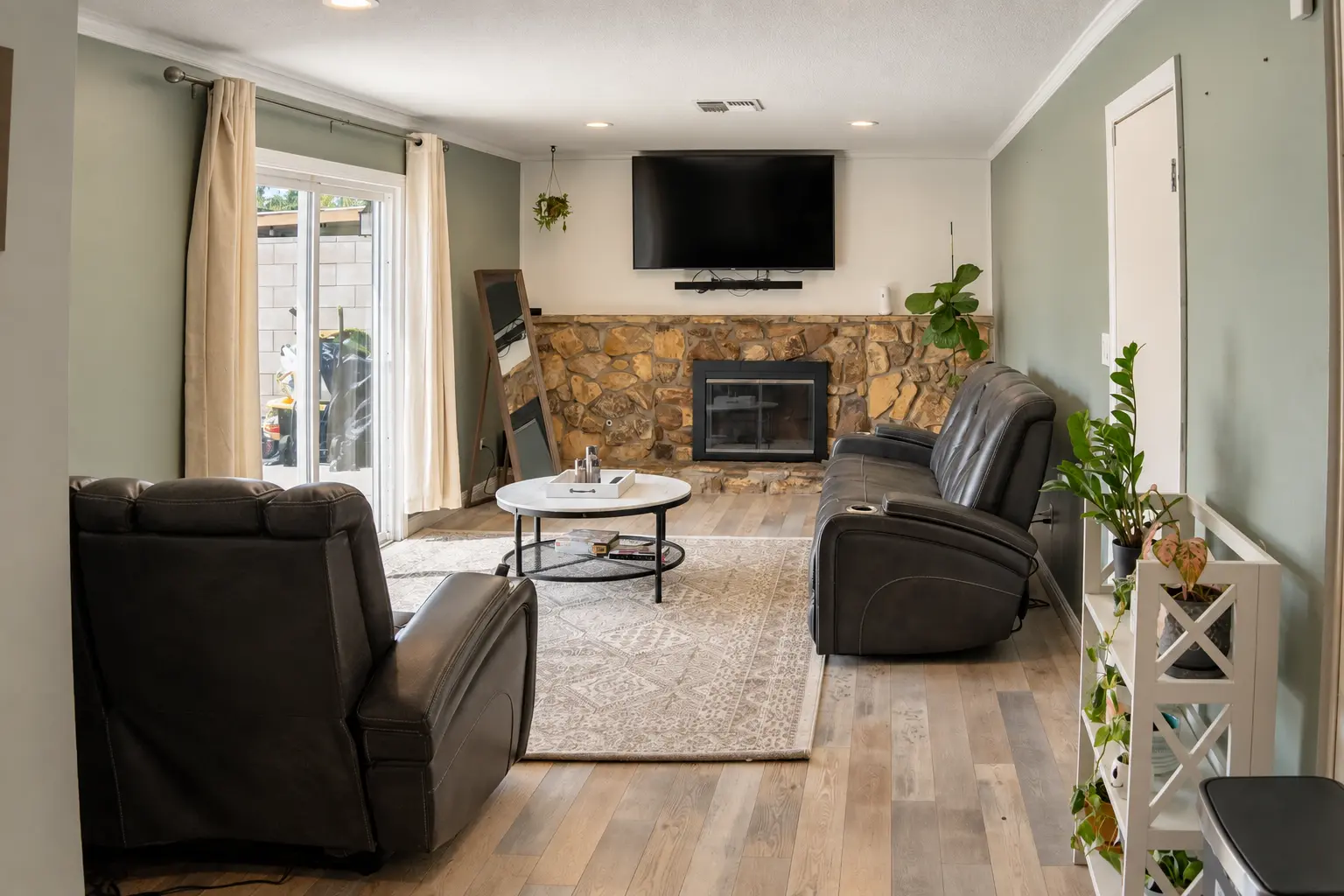 Living room with stone fireplace and mounted TV
